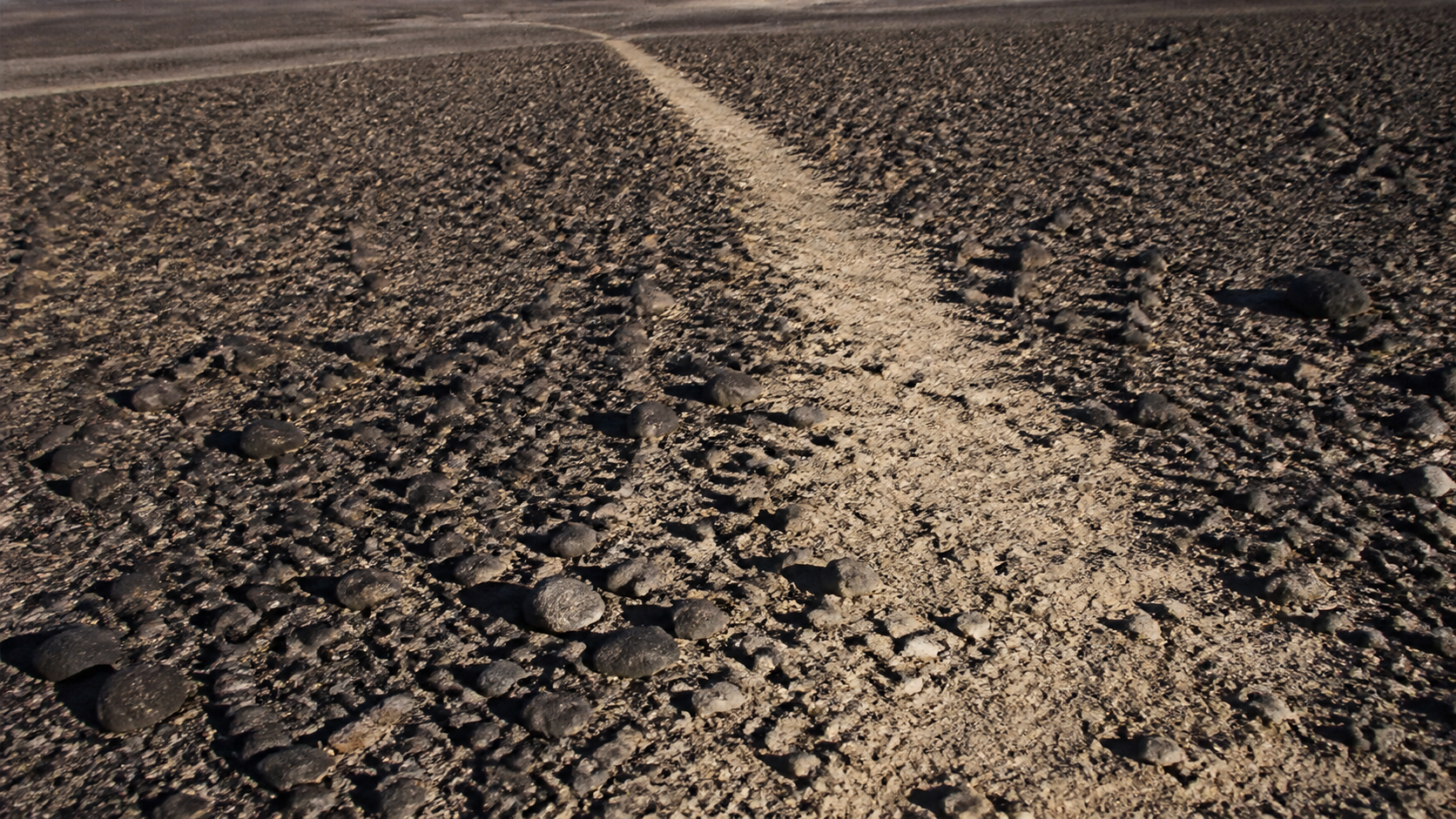 Detalhe conceitual de pedras escuras afastadas para revelar solo claro em um geoglifo
